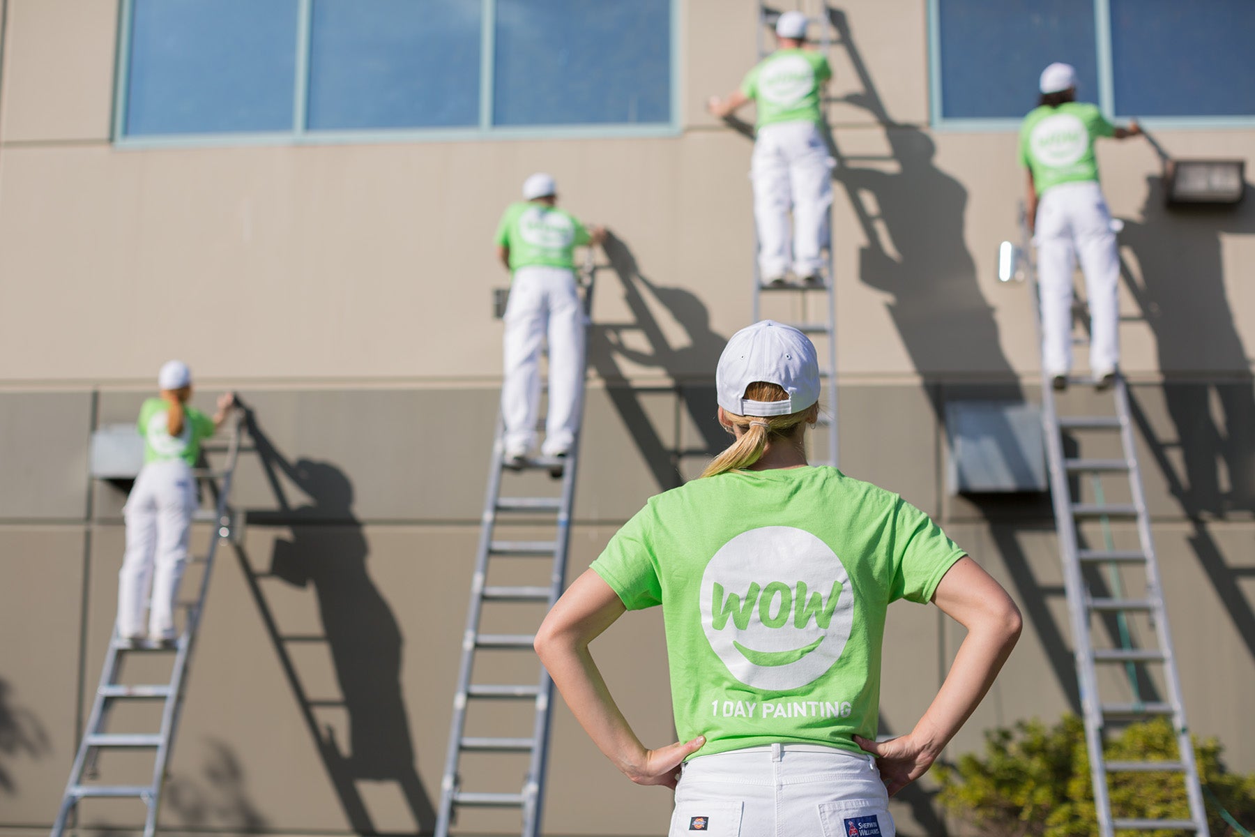 wow1daypainting happy employees in uniform painting building